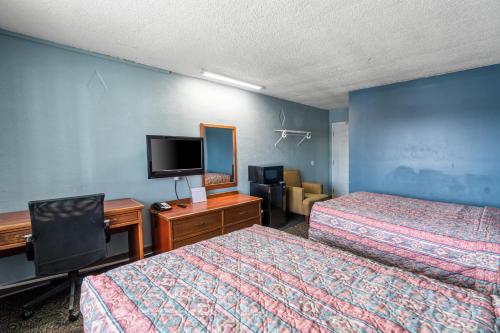 a hotel room with two beds and a flat screen tv at Broadway Inn in Council Bluffs