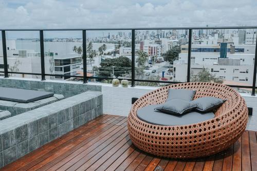 una sedia in vimini su un balcone con vista sulla città di Charmoso Flat - Pôr-do-Sol do Jacaré a Tambaú