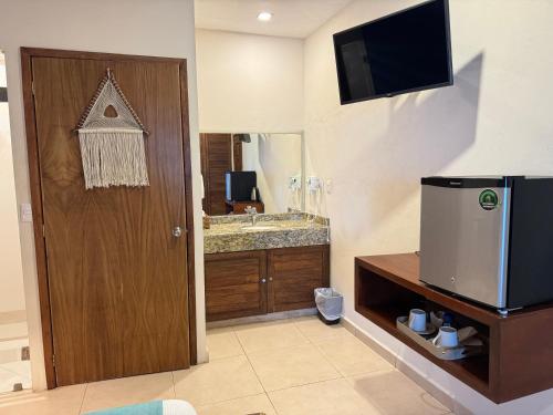 a bathroom with a sink and a door with a television at Suites Valentina in Puerto Morelos