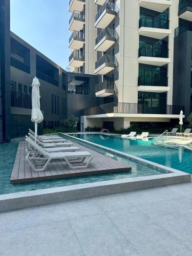 a swimming pool with chairs and an umbrella and a building at Capsule Flora business bay view Burj Khalifa-pool table-game arcade-Projector-Playstation 5 in Dubai