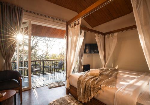 a bedroom with a canopy bed and a balcony at Moustache Bhimtal Luxuria, Nainital in Bhīm Tāl