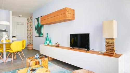 ein Wohnzimmer mit einem Flachbild-TV an einer weißen Wand in der Unterkunft Beachstyle Penthouse by Hello Homes Sitges in Sitges