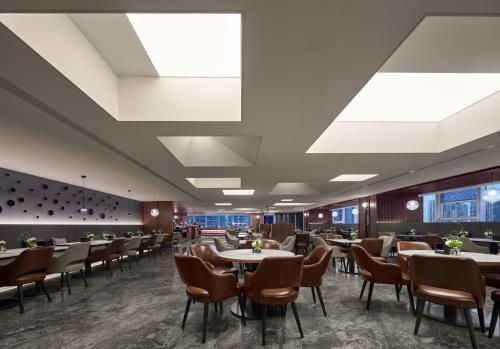 una sala da pranzo con tavoli, sedie e finestre di Hefei Huiyan Anhui Center Intercity Hotel a Hefei