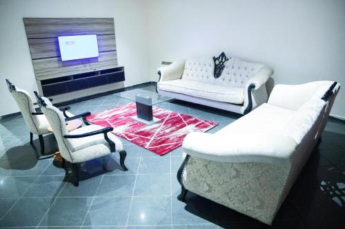 a living room with a couch and chairs and a tv at Lamonde Bysomwhere in Jos