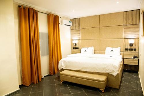 - une chambre avec un grand lit et des rideaux orange dans l'établissement Lamonde Bysomwhere, à Jos