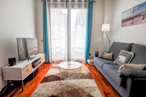 een woonkamer met een blauwe bank en een tv bij Seaside April Apartment by Hello Homes Sitges in Sitges