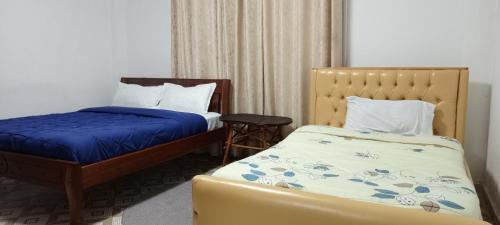 a bedroom with two beds and a chair in it at Pavleena Residence 2 Bedrooms unit in Nanyuki