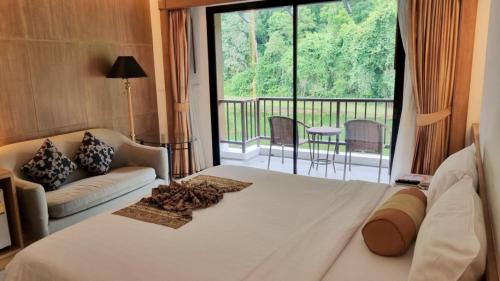カトゥーにあるTinidee Golf Resort Phuket - SHA Extra Plusのベッドルーム(大型ベッド1台、バルコニー付)