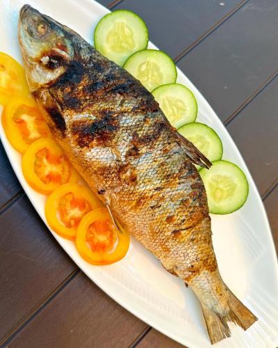 a plate of fish and vegetables on a table at Lotus Sun & Waves Beach Resort in Baler