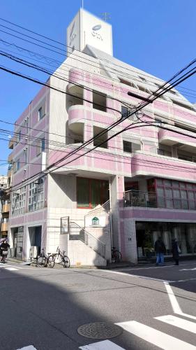 a white and pink building on a city street at The Evergreen Hostel 長期ステイ歓迎 エバーグリーンホステル in Hiroshima