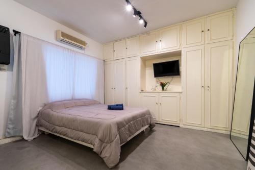 1 dormitorio con 1 cama, armarios blancos y TV en Apartamento zona Embajada USA - Plaza Italia by Debarrio Aparts en Buenos Aires