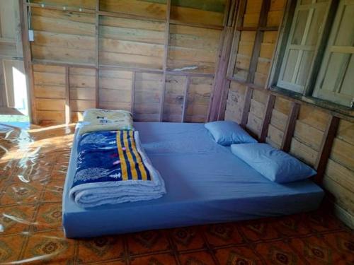 uma grande cama azul num quarto de madeira em Shared Happy Farm em Ban Nongboua