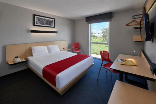 Habitación de hotel con cama, escritorio y ventana en City Express by Marriott Irapuato Norte, en Irapuato