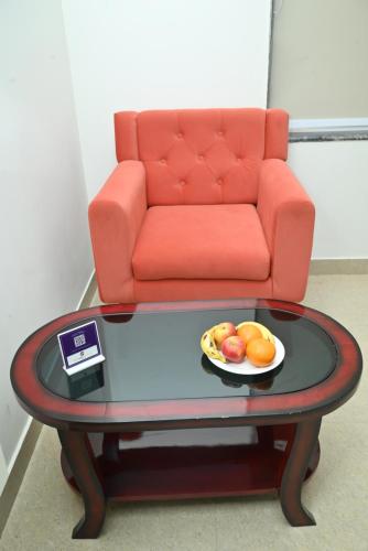 a table with a bowl of fruit and a couch at Click Hotel Narayana in Ayodhya