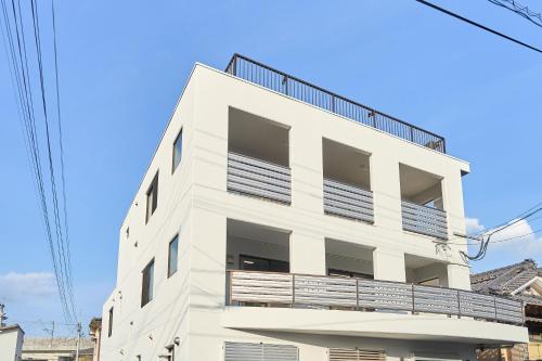 a white building with a balcony on the side of it at BETTEI in Oita