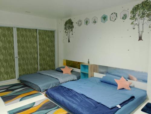 2 Betten in einem Schlafzimmer mit grünen Wänden in der Unterkunft พญาเกสท์เฮ้าส์ in Nakhon Phanom