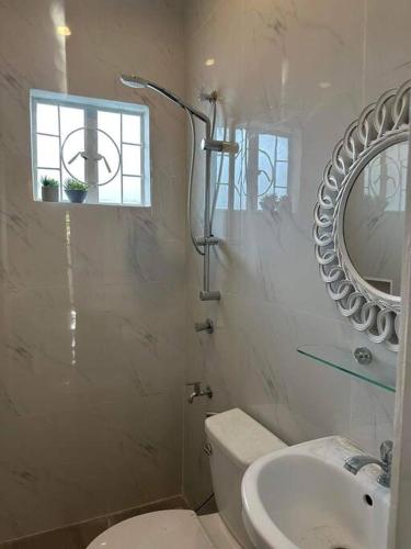 a bathroom with a toilet and a sink and a mirror at Japandi Home A - Fully Aircon, WIFI, Hot shower, 24hGuard, Center, near Malls in General Santos