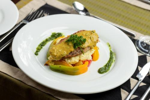 a white plate with a sandwich and vegetables on a table at The Weir House in Ulapane