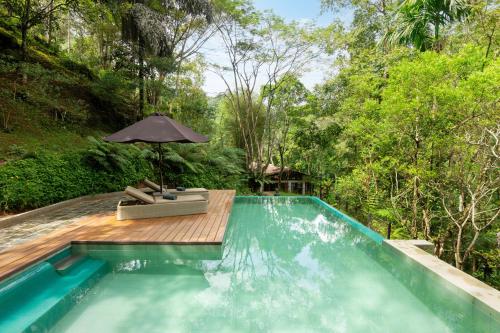 a swimming pool with a chair and an umbrella at The Weir House in Ulapane