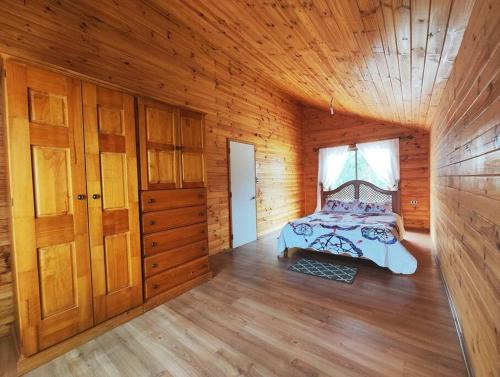 een slaapkamer met een bed in een houten hut bij Casa en la Perla del Maule in Constitución