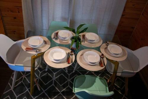 a glass table with plates and a plant on it at Casa en la Perla del Maule in Constitución