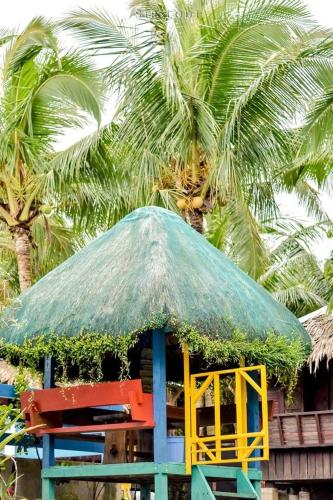 a hut with a straw umbrella and a table and chairs at Lotus Sun & Waves Beach Resort in Baler