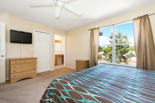 a bedroom with a bed and a tv and a window at Paradise Palms By Mid Florida Home Management in Orlando
