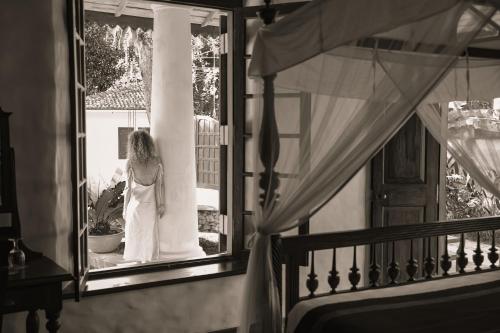 a woman in a wedding dress looking out of a window at Heenatigala Walawwa in Talpe