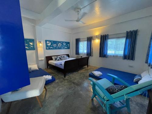 a room with a bed and a couch and chairs at Chalaroste Place by SMS Hospitality in Bolinao