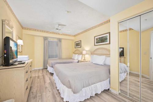 a bedroom with two beds and a flat screen tv at Luxury 10th Floor 1 BR Condo Direct Oceanfront Wyndham Ocean Walk Resort Daytona Beach | 1006 in Daytona Beach