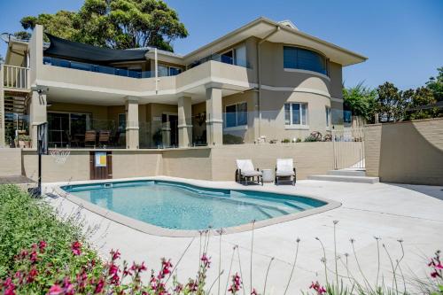 a house with a swimming pool in front of a house at Anchors at Mollymook Beach in Mollymook