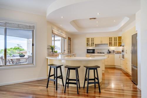 a kitchen with a large island with stools at Anchors at Mollymook Beach in Mollymook