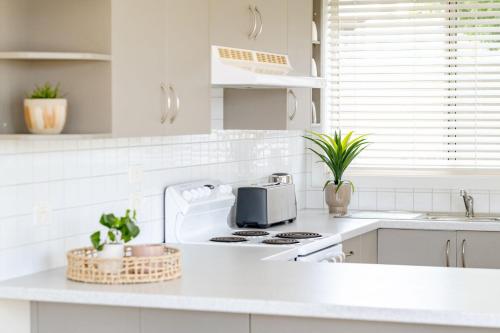 a white kitchen with a stove and a sink at Anchors at Mollymook Beach in Mollymook