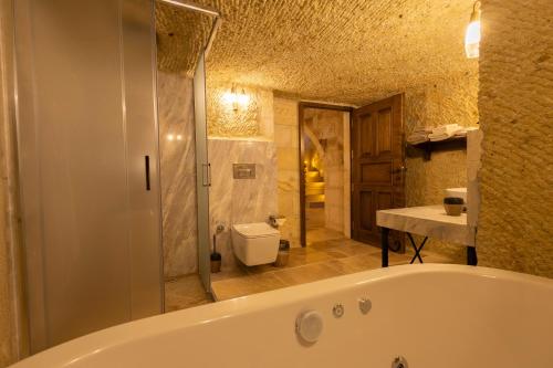 a bathroom with a tub and a toilet and a sink at Seraphim Cave Suites & SPA in Urgup