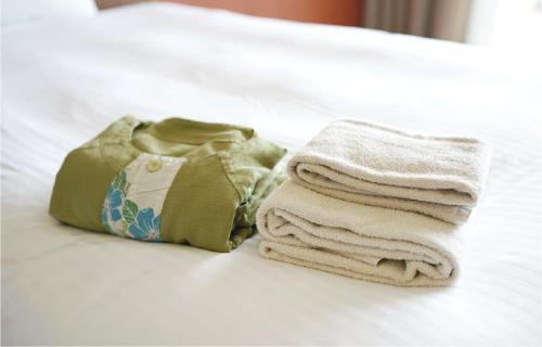 a pile of towels sitting on top of a bed at EM Wellness Kurashinohakko Lifestyle Resort in Kitanakagusuku