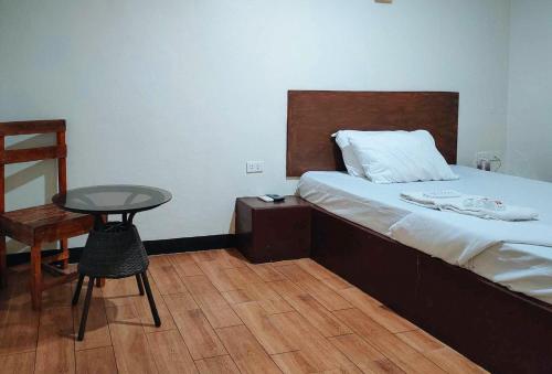 a bedroom with a bed and a table and a chair at RedDoorz @ Linda Ford Residences in Puerto Princesa City
