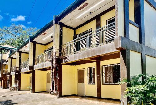 a yellow building with balconies on a street at RedDoorz @ Linda Ford Residences in Puerto Princesa City