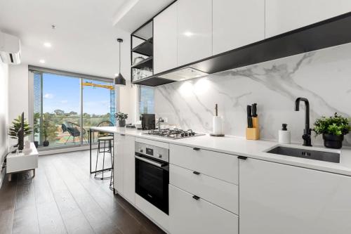 - une cuisine blanche avec cuisinière et évier dans l'établissement Grandeur Apartment, à Melbourne