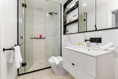 a white bathroom with a sink and a shower at Grandeur Apartment in Melbourne