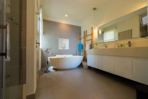 La salle de bains est pourvue d'une grande baignoire blanche et d'un lavabo. dans l'établissement Beautiful 3 bed-room beachfront penthouse, à Grand Baie