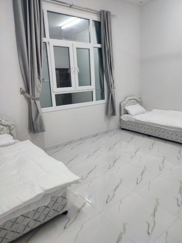 a bedroom with white marble floors and a window at Jabal Shams, Al Noor house جبل شمس in Misfāh
