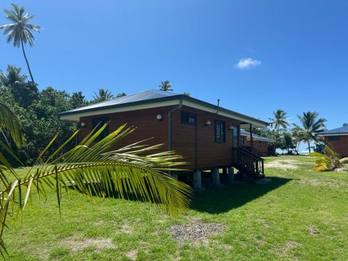 Parea的住宿－Parea Lodge Huahine BUNGALOW F2 #Miti，一座小木房子,前面有一棵棕榈树
