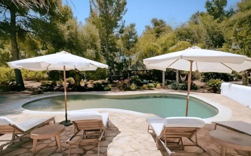 a pool with chairs and umbrellas in a yard at La Finca Agroturismo Can Bet in Santa Eularia des Riu