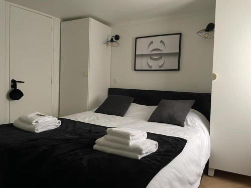 ein Schlafzimmer mit einem schwarzen und weißen Bett mit Handtüchern darauf in der Unterkunft Élégant Appartement près du Musée du Louvre et du Jardin des Tuileries in Paris