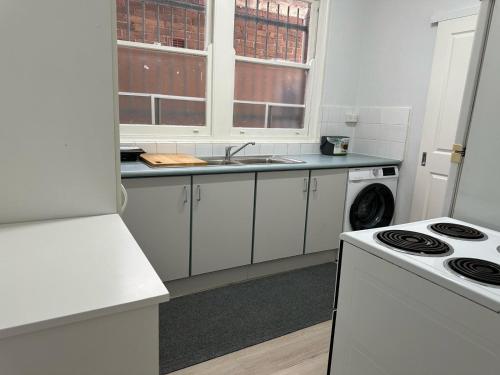 a white kitchen with a sink and a stove at ROOM - BEXLEY NORTH in Sydney