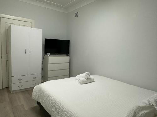 a white bedroom with a bed and a tv at ROOM - BEXLEY NORTH in Sydney