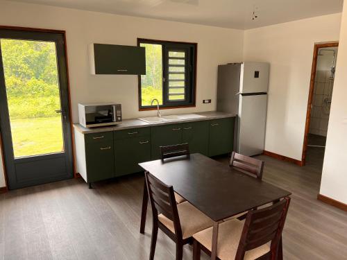 cocina con armarios verdes, mesa y nevera en Parea Lodge Huahine BUNGALOW F2 #Miti, en Parea