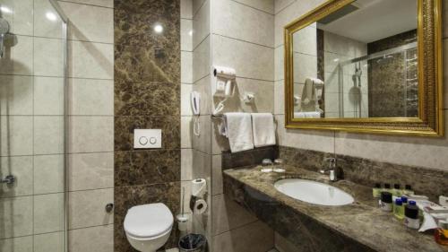 a bathroom with a sink and a toilet and a mirror at Alan Xafira Deluxe Resort & Spa-ULTRA ALL INCLUSIVE in Alanya
