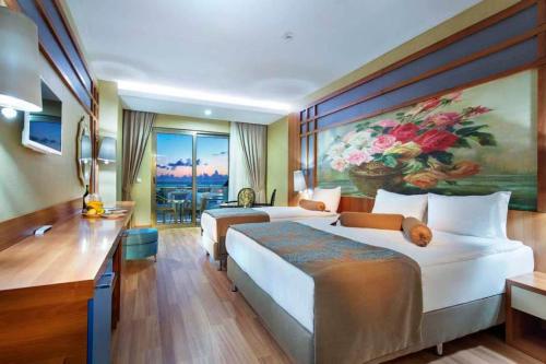a bedroom with two beds and a painting of flowers at Alan Xafira Deluxe Resort & Spa-ULTRA ALL INCLUSIVE in Alanya