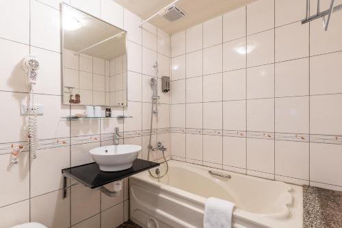 a white bathroom with a sink and a tub at Guide Hotel Taipei Dadaocheng in Taipei